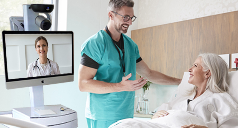 Telehealth cart beside a hospital bed while a health professional communicates with patient.
