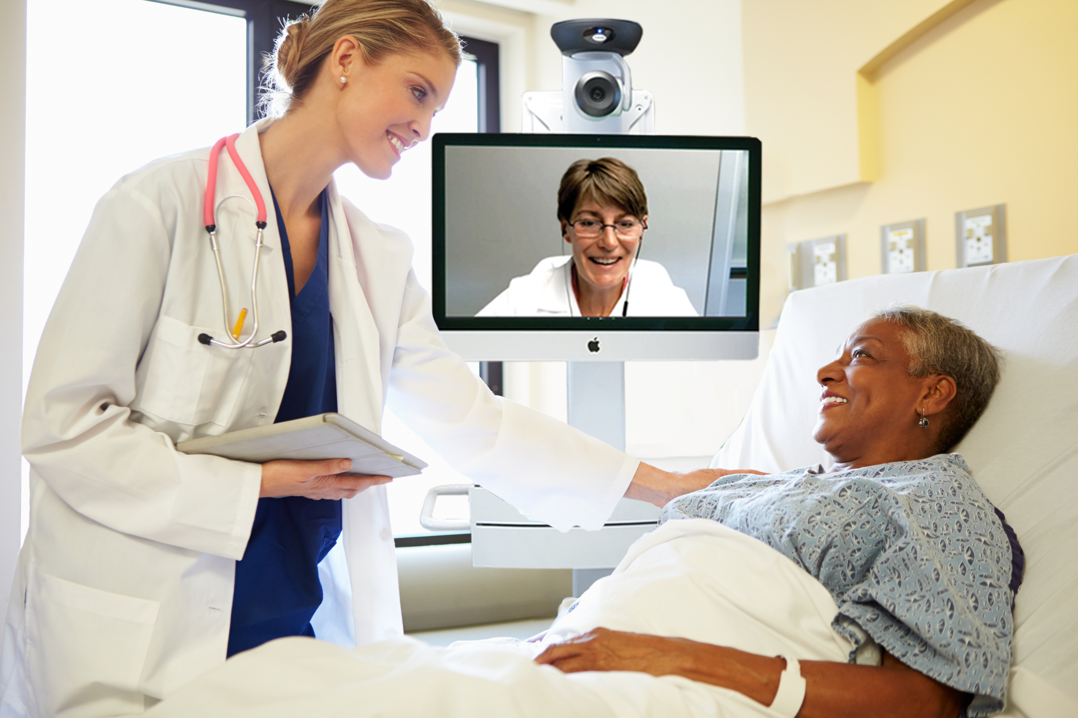 teleNeurologist on Access TeleCare cart and doctor talking to patient in hospital bed