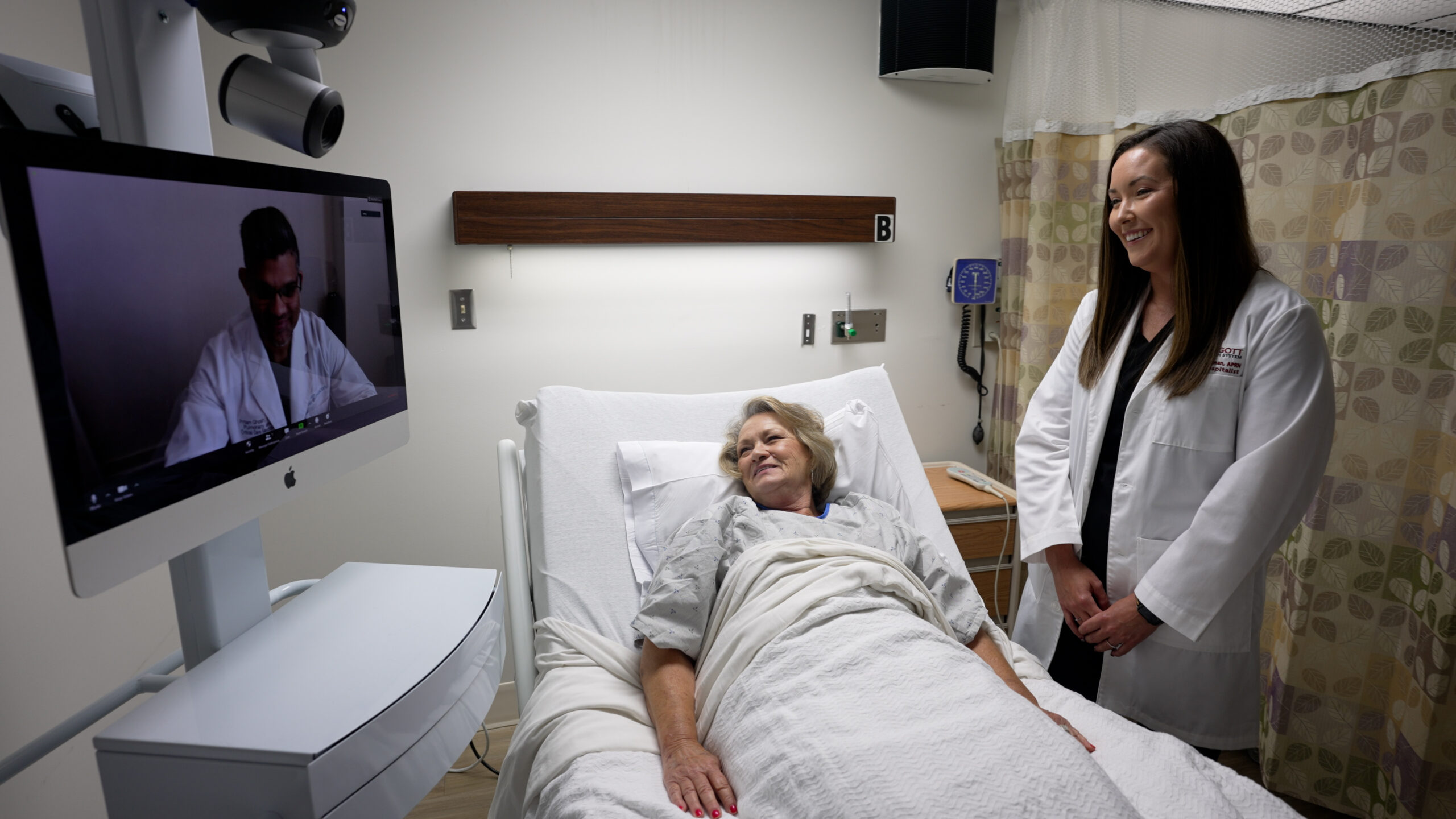 Doctor standing with patient and an Access TeleCare telemedicine cart